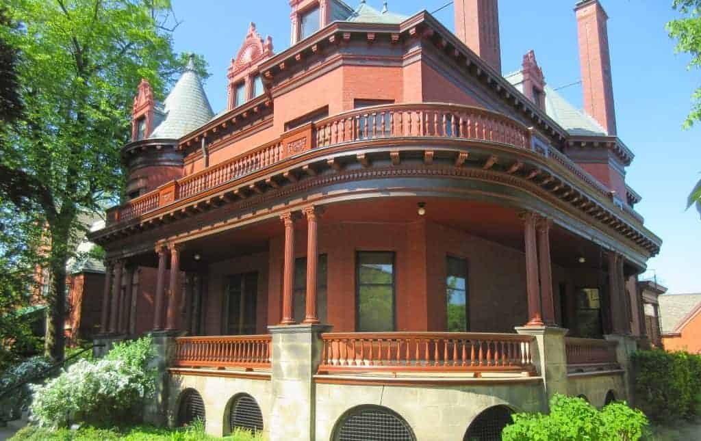 Restored Victorian home with red brick and ornate porch, showcasing home restoration Michigan